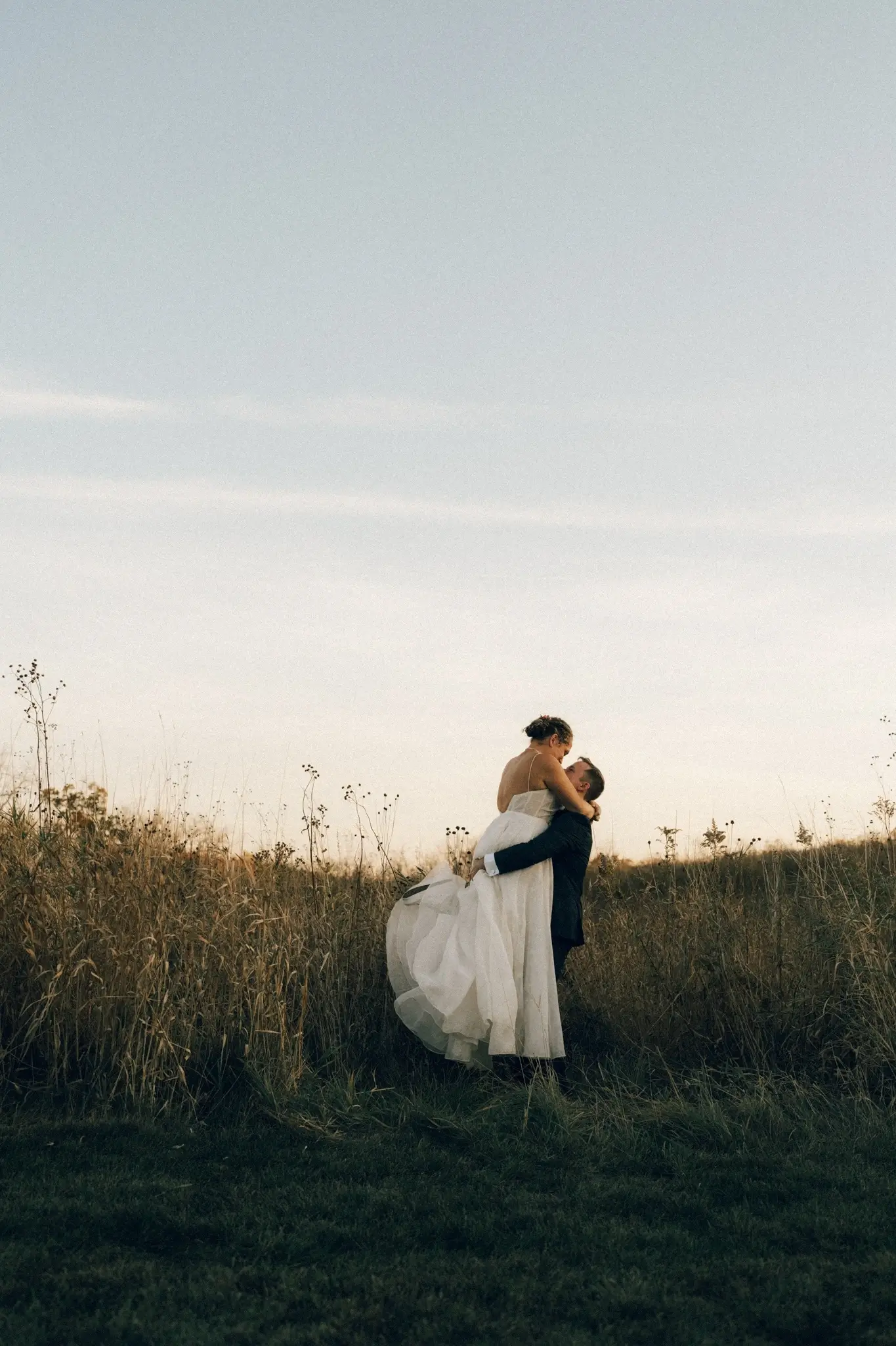 Groom lifts bride in a golden field during an intimate Minnesota elopement