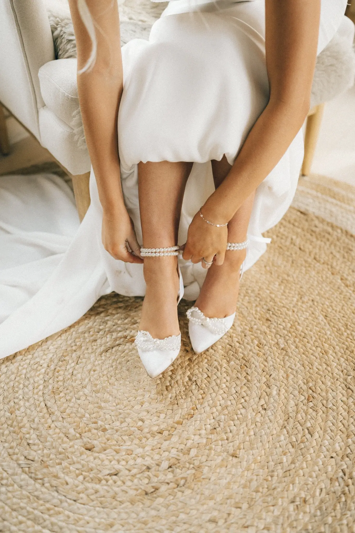 Bride adjusting pearl ankle straps on wedding shoes