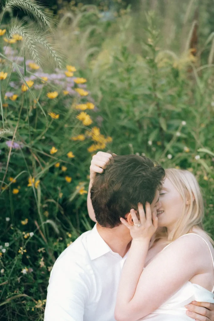 Couple engagement session embracing and kissing in a wildflower meadow