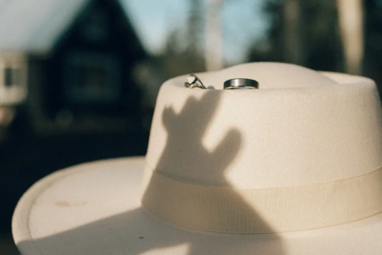 engaged couple holding hands with engagement rings placed on hat