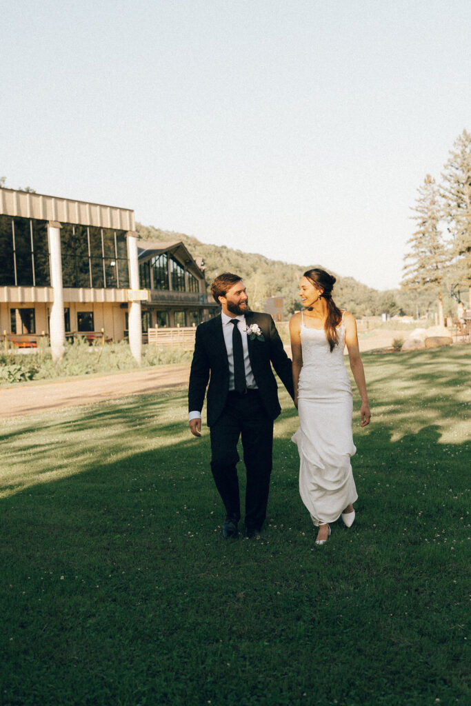 bride and groom walk hand-in-hand while laughing with each other