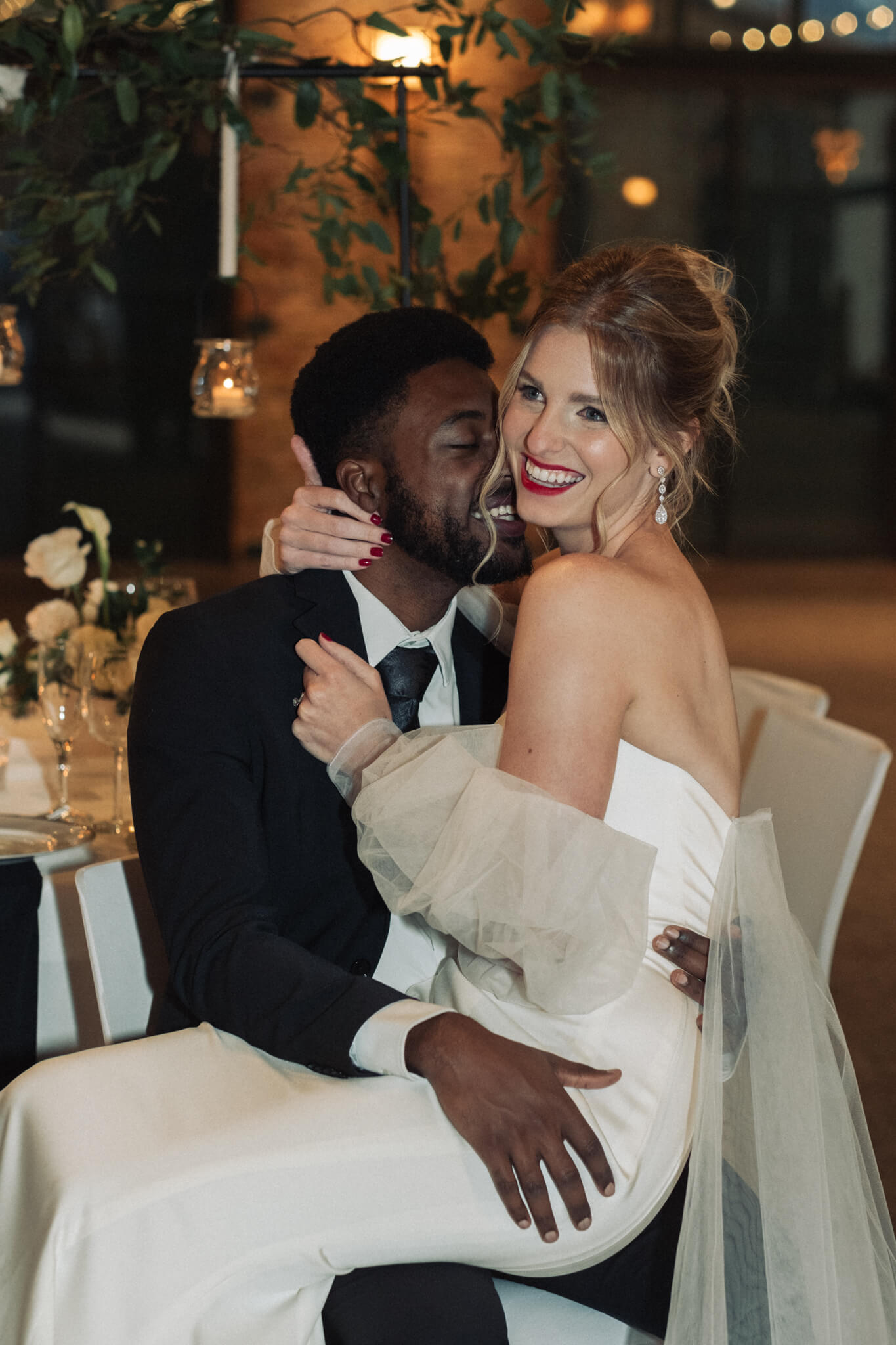 bride and groom embrace while sitting on chair together
