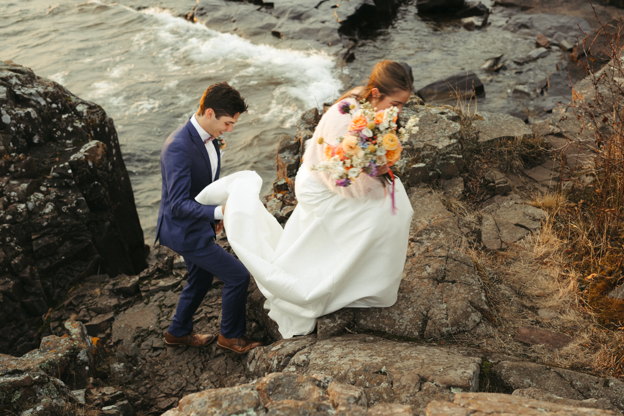 eloping bride and groom climb the cliffs of lake superior in minnesota